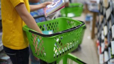 Çocuk okul malzemelerini seçiyor. Okul malzemeleriyle alışveriş arabası.
