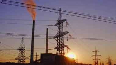 Elektrik direkleri ve halatlar alacakaranlıkta. Yüksek voltaj kulesi ve kablolardan oluşan siluet