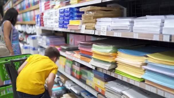ショッピングモールの子供 ストアで学校の文房具を選ぶ少年 — ストック動画