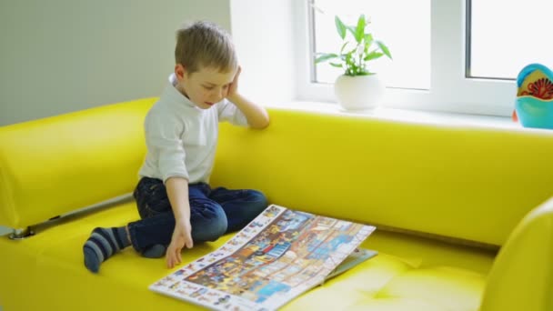 自宅で本を持った少年 彼の部屋で本を読んでいる小さな少年 — ストック動画