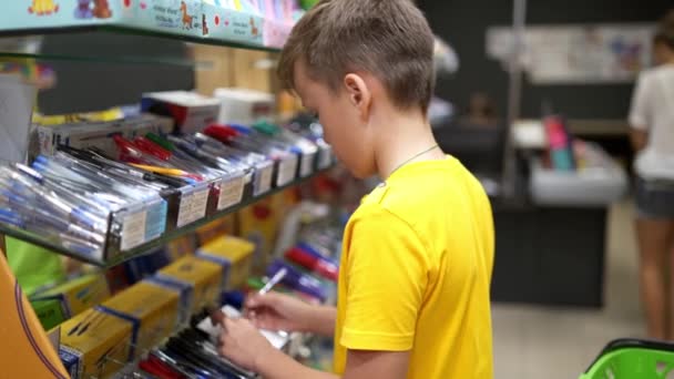 学校の文房具を持った子供たち 学校に戻るために買い物をする少年 — ストック動画