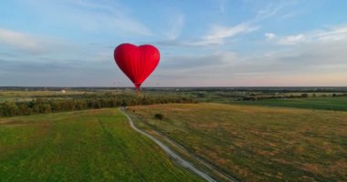 Gökyüzünde kırmızı balon. Tarlaların üzerinde kalp şeklinde balon