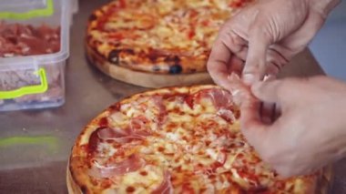 Şef pizza yapıyor. Fırıncı elleri pizzaya malzeme koyuyor.