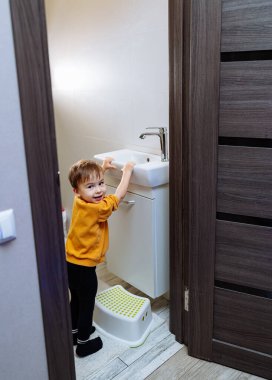 Lavabonun önünde duran küçük bir çocuk. Banyonun Harikalarını Keşfeden Meraklı Küçük Bir Çocuk