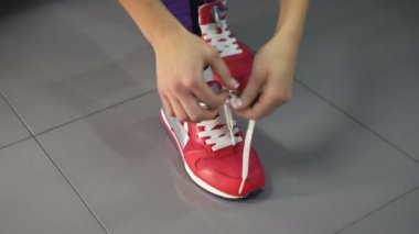 Eğitimden önce ayakkabı bağcıkları bağlayan bir sporcu. Spor ayakkabı bağcıklarını spor salonunda bağlayan kadın.