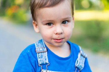Mavi gömlek ve pantolon askısı giyen genç bir çocuk. Mavi gömlek ve pantolon askısı takan genç bir çocuk.