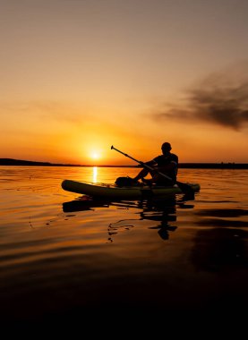 Sunset 'te Sakin Kano Macerası. Gün batımında bir kano üzerinde bir insan.