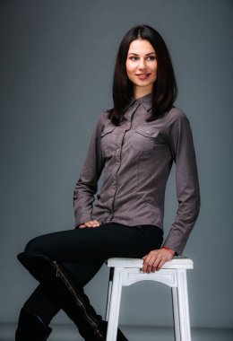 Büyüleyici bir portre: Bir kadın fotoğraf için tabureye zarif pozlar verir. Taburede oturup poz veren bir kadın.