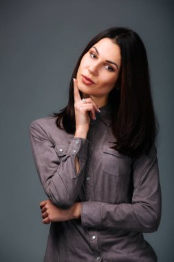 Huzurlu bir güzellik, düşünceli bir şekilde ele geçirilmiş, özünü kucaklayan. Eli çenesinde poz veren bir kadın.