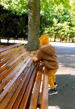 Parktaki Oyuncak Ayı. Parktaki bankta oturan ayı kostümlü küçük bir çocuk.