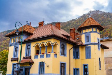 Görkemli Dağlar ve Açık Mavi Gökyüzü ile çevrili Renkli bir bina. Arkasında dağ olan sarı ve mavi bir bina.