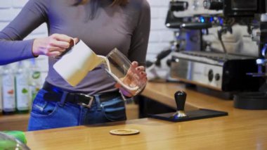 Kahve dükkanında çalışan barista. Kahve yapan bayan barista kafe tezgahının arkasında dikiliyordu.