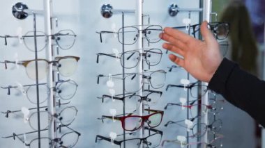 Optik mağazada gözlük seçen bir adam. Optik mağazada gözlük çerçevesi seçen yakışıklı genç adam.