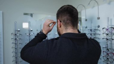 Optik dükkanında gözlük deneyen bir adam. Mağazada gözlük seçen erkek hasta