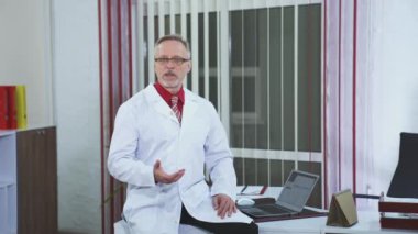 Çevrimiçi konferans doktoru kameraya bakıyor. Doktorun klinikte kamerayla konuşmasının ön görüntüsü