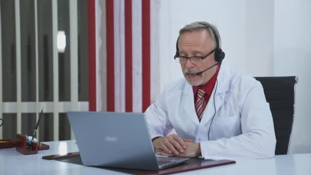 Online Medical Consultancy Senior Old Doctor Wears Headset Looking Camera — Stock Video