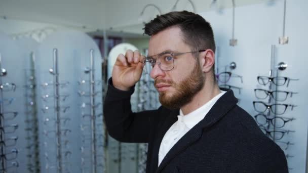 Hombre Eligiendo Gafas Tienda Óptica Joven Tienda Óptica Probando Anteojos — Vídeo de stock