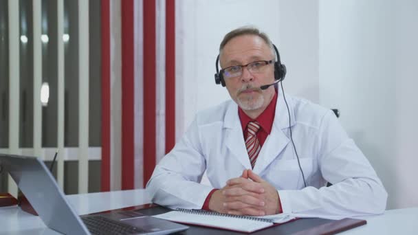 在线会议医生在诊所 在视频通话中 英俊成熟的医生会诊病人 — 图库视频影像