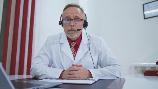 医生在用笔记本电脑上网工作 高级医生在笔记本电脑上与病人进行视频交谈 — 图库视频影像