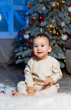 Noel ağacının önünde oturan bir bebek. Neşeli bir bebek Noel Ağacı 'na hayran