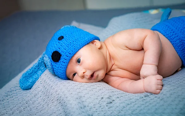 A baby wearing a blue crochet hat laying on a blanket. Baby in a Blue Crochet Hat