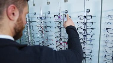 Adam dükkandan bardak alıyor. Yakışıklı adam gözlüğü mağazada ölçüyor.