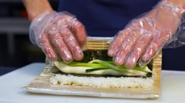 Restoranda suşi pişirme işlemi. Mutfakta suşi pişirirken eldivenli şefin ellerini kapat.