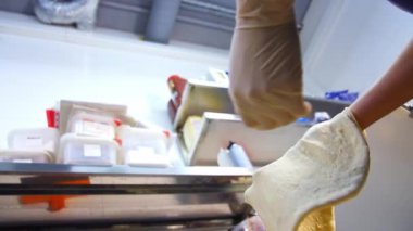 Aşçı mutfakta hamur pişiriyor. Üniformalı şef pizza çeviriyor ve atıyor.