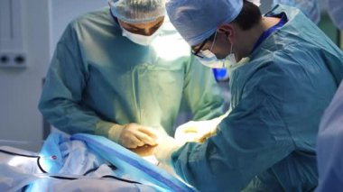 Hastanede cerrah ameliyatı. Tanınmayan cerrahlar enstrümanı hastanın karnında tutuyorlar.