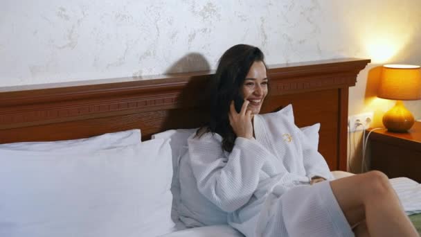 Жінка Лежить Ліжку Готелі Щаслива Жінка Телефонує Смартфон Готельному Номері — стокове відео