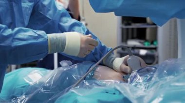 Modern ameliyathanede tıbbi uzmanlar. Doktorlar bir ameliyat yapıp işleme monitörden bakıyorlar. Video.