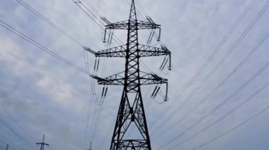 Enerji dağıtım ağı. Elektrik direkleri turuncu ve sarı günbatımına karşı. Seçici odak.