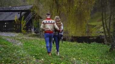 Romantik çift dışarıda birbirlerine sarılarak yürüyor. Sonbahar doğa geçmişi. Arkadan bak. Aşk hikayesi videosu.