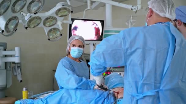 在配备现代化设备的诊所工作 带显微镜的外科一组戴着医疗面具和制服的医生 屏幕与过程 — 图库视频影像