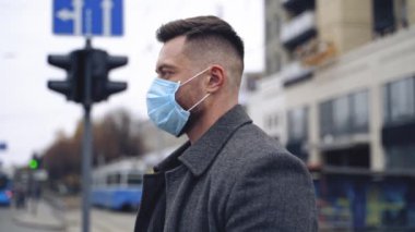 COVID-19. Sokaktaki adam koronavirüs yayılmasına karşı yüz koruyucu maske takıyor. Ceketli ve takım elbiseli bir erkek portresi..