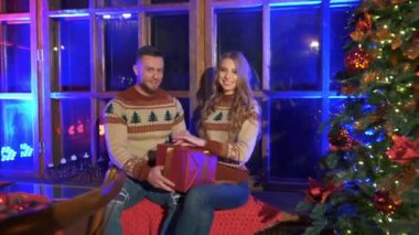 Yeni evliler, Noel ağacının yanında Noel süveteri giyip Noel ağacı tutuyorlar..