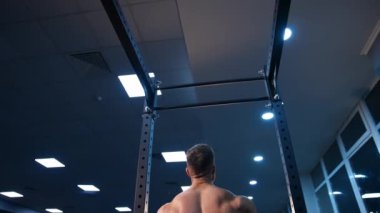 Horisontal bara yapışmış yakışıklı bir adam. Spor salonunda erkek sporcu eğitimi. Yavaş çekim.
