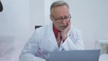 Doktor masasında oturuyor ve işyerindeki zor vakayı düşünüyor.