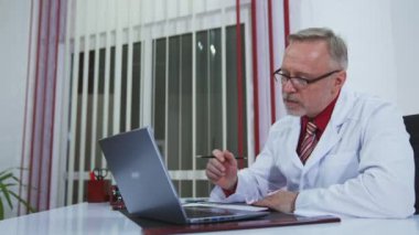 Doktor internetten hastalarla sohbet ediyor, iş yerinde dizüstü bilgisayar kullanıyor. Teletıp kavramı
