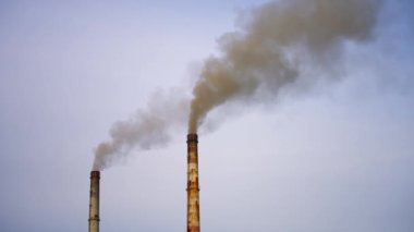 Dumanlı fabrika boruları. Kirli duman, bacalardan nehrin arka planındaki havaya yayılıyor. Hava görüntüleme videosu.