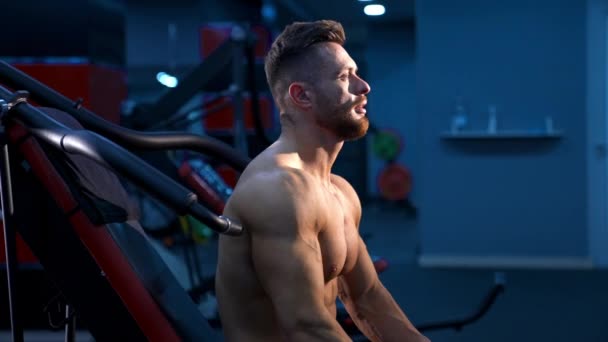 凶残强壮的运动员抽动肌肉 在运动器材上做运动 肌体健美运动员在健身房用赤身裸体做运动 健身和健美的概念 侧边录像 — 图库视频影像