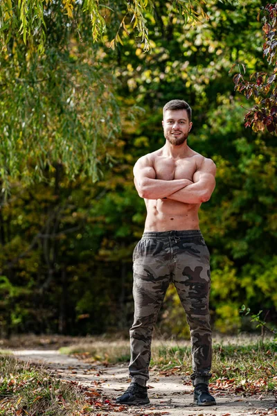 Shirtless Man with Crossed Arms on a Path. A shirtless man standing on a path with his arms crossed