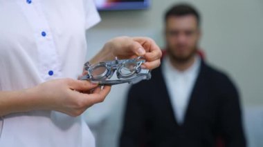 Kadında oftalmolojik deney çerçevesi ve test gözlüğü var. Göz düzeltmesi. Geçmişi bulanık genç bir adam..