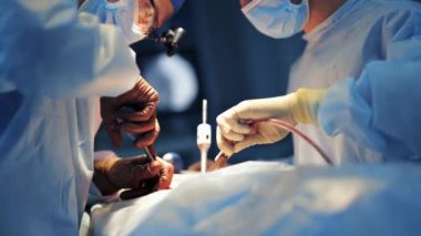 Ellerinde özel aletler bulunan iki profesyonel beyin cerrahı modern klinikte hastayı ameliyat ediyor. Önlüklü tanınmayan sağlık görevlileri.