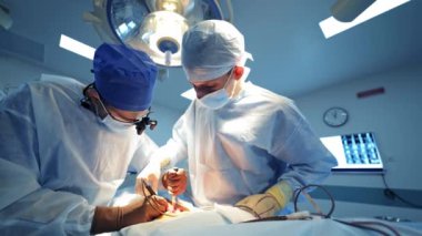 Ameliyathanede bir grup doktor var. Mavi maskeli ve üniformalı tıp uzmanları klinikte ameliyat yapıyorlar. Tıbbi sinir cerrahisi aletleri ve ekipmanları.