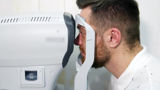 眼科诊所的男性病人用特殊的现代设备检查视力 有选择地关注男人的脸 — 图库视频影像