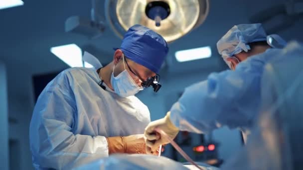 経験豊富な医師の神経外科医は明るいライトが付いている現代医院の部屋の特別な装置との困難な操作を提供します — ストック動画