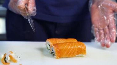 Şef keskin bıçakla suşiyi parçalara ayırır. Suşi pişirme, hazırlanma süreci. Japon mutfağı kavramı.