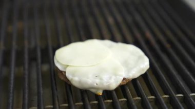 Üstünde yumurta olan hamburger pirzolası büyük bir ızgarada kızartılır. Fast food konsepti. Lezzetli video.