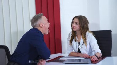 Klinikte canlı konsültasyon. Kadın doktor, modern klinikte kıdemli doktorla konuşuyor. Yavaş çekim videosu.